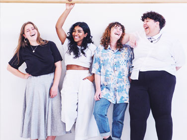 Four gender non-conforming young people standing in a row laughing, seemingly good friends. Examples of gender non-conforming people who choose a Connecticut nurse-midwife for their sexual and reproductive, well-person healthcare.
